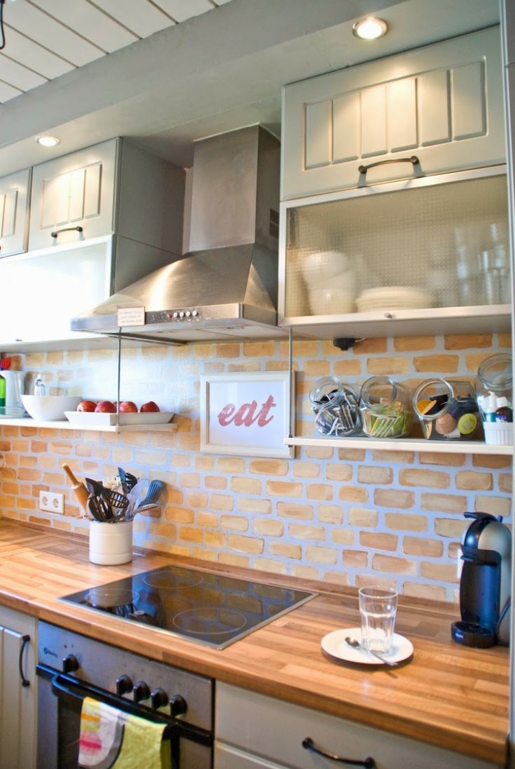 Светлая кухня с отделкой стеновой панели из камня дополнена идеальной деревянной столешницей